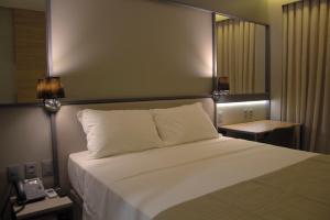 a bedroom with a white bed with two lamps and a phone at Slaviero Campina Grande in Campina Grande
