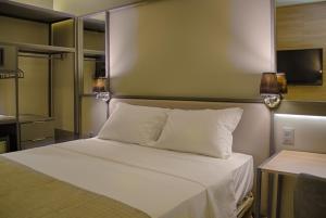 a bedroom with a white bed with two lights on the wall at Slaviero Campina Grande in Campina Grande