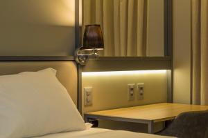 a bedroom with a bed with a lamp and a mirror at Slaviero Campina Grande in Campina Grande