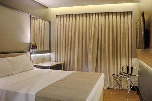 a bedroom with a bed and a window with curtains at Slaviero Campina Grande in Campina Grande