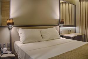 a bedroom with a large white bed with a mirror at Slaviero Campina Grande in Campina Grande