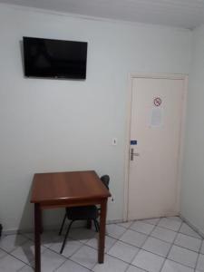a room with a wooden table with a television on a wall at Hotel Barão Do Rio Branco in Bebedouro