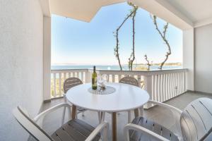 a white dining room with a white table and chairs at Apartments Martom in Seline