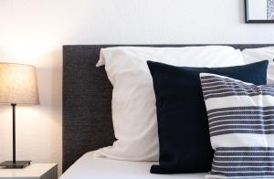 1 cama con almohadas blancas y negras y lámpara en Helles Design-Appartement an der Messe, en Essen