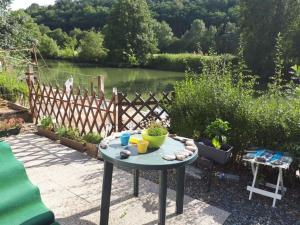 a table in a garden with a view of a river at Caravane au bord de la rivière in Saint-Corneille
