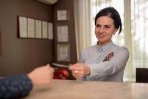 a woman in a red shirt is looking at a piece of paper at Weekend Boutique Hotel in Chişinău