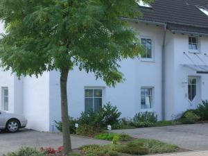 Una casa blanca con un árbol delante. en Ferienwohnung Im alten Feld en Schmallenberg