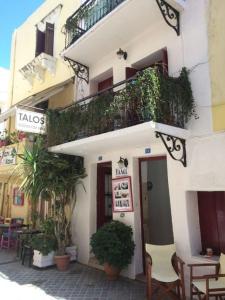 a white building with a balcony and tables and chairs at Talos in Chania Town