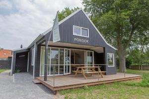 a black house with a wooden deck and a table at Vakantiehuis de Pondok in Gaastmeer