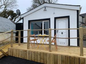 a tiny house with a deck with a table on it at Lagoon View Cottage in Millisle