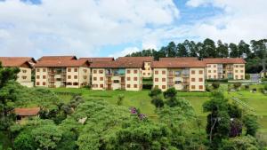 a large apartment building on a hill with trees at Apartamento Vista para as Montanhas in Campos do Jordão