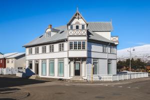 una casa blanca con una torre en una calle en Hoepfner and Tulinus Historical Houses, en Akureyri