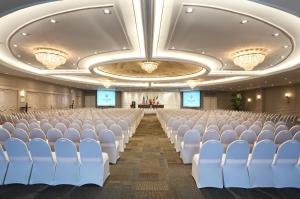 una sala de conferencias con sillas blancas y un escenario en Oro Verde Guayaquil, en Guayaquil