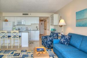 sala de estar con sofá azul y cocina en Ocean Forest Plaza by Palmetto Vacations, en Myrtle Beach