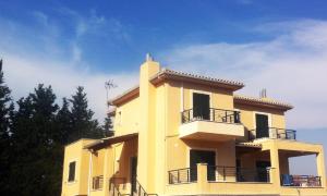 un edificio amarillo con balcón y cielo azul en Villa Salomi, en Lefkada