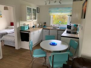 uma pequena cozinha com uma mesa e cadeiras e uma cama em 24 Gower Holiday Village em Reynoldston