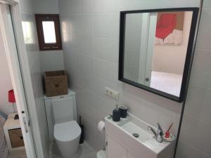 ein Badezimmer mit einem WC, einem Waschbecken und einem Spiegel in der Unterkunft A Guaira, fantástico apartamento al borde del mar in Oia