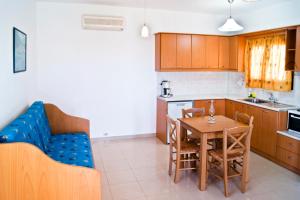 a kitchen with a table and a blue couch at Fotini Apartments in Palekastron