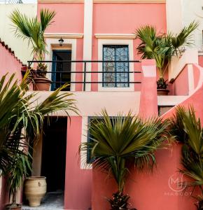 uma casa cor-de-rosa com palmeiras em frente em Mascot Garden Rooms em Rodes