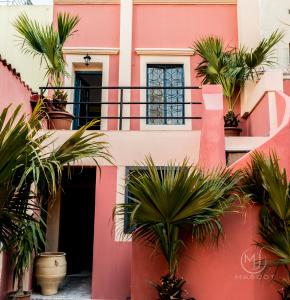 een roze huis met palmbomen ervoor bij Mascot Garden Rooms in Rhodos-stad