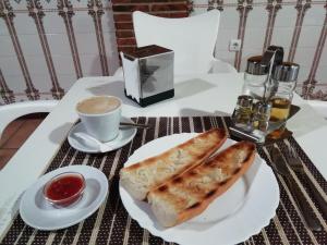 Hostal Zaguan في Talaveruela: طاولة مع صحن من الخبز وكوب من القهوة