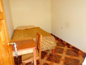 a small room with a table and a bed and a door at Hospedaje Inti in Pisac