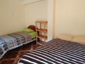 a bedroom with two beds and a book shelf at Hospedaje Inti in Pisac