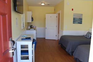 Habitación pequeña con cama, escritorio y cocina. en Topsail Shores Inn en Sneads Ferry