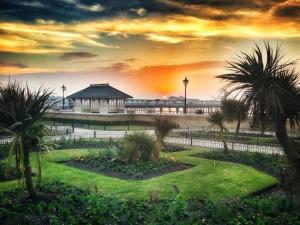 a park with a building and a garden with palm trees at Imperial House Holiday Let in Herne Bay