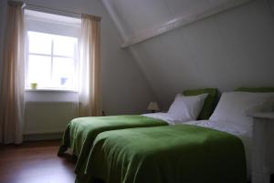Un dormitorio con dos camas con sábanas verdes y una ventana. en Bed&Brood De StraVerdonk, en Graft