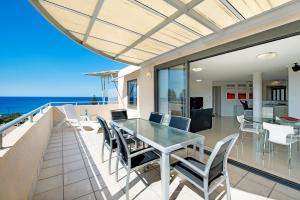 a dining room with a glass table and chairs on a balcony at ULTIQA Shearwater Resort in Caloundra