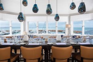 a dining room with a table and chairs and windows at Anchorage Port Stephens in Nelson Bay