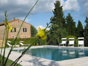 a view of a pool with chairs and a house at Certine Agriturismo in Asciano