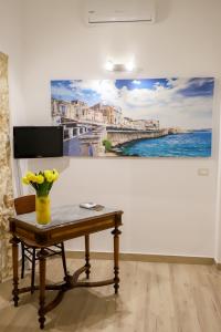 uma mesa com um vaso de flores na parede em La Sicilia in un sogno em Siracusa