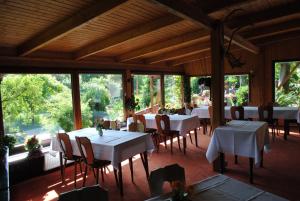 a dining room with white tables and chairs and windows at Hotel Ruhekrug in Schleswig