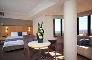 a hotel room with a bed and a table with flowers at Stamford Grand Adelaide in Adelaide
