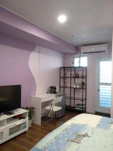 a bedroom with purple walls and a desk and a tv at Happy宅 in Tainan