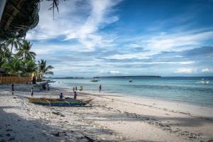 un grupo de personas en una playa con un barco en Sunrise Beach Club Resort Amanecer, en Bantayan Island