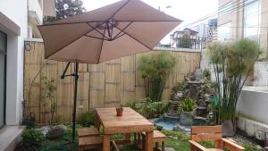 an umbrella in a garden with a table and benches at Suites+Arte in Quito