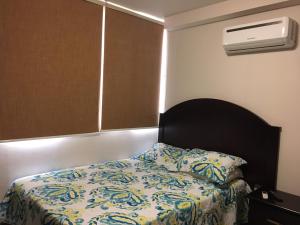 um quarto com uma cama com um edredão e uma almofada em Apartamento Climatizado, 2 Habitaciones y Piscina em Tegucigalpa