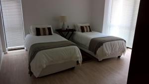 two beds in a room with two windows at Milkwood House in Wilderness +3 photos