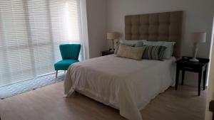a bedroom with a large bed and a blue chair at Milkwood House in Wilderness