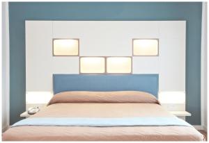 a bedroom with a bed with four lights above it at Hotel Dante in Lido di Jesolo