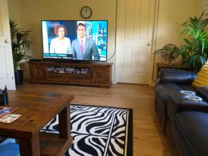 a living room with a flat screen tv and a couch at Middle Ridge, Toowoomba, in Toowoomba