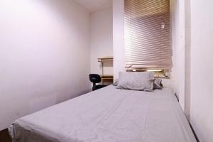 a white bedroom with a bed with a window at Wiens Residence BSD in Tangerang