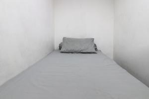 a small bed in a white room with a pillow at Wiens Residence BSD in Tangerang