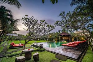 einen Pool mit roten Stühlen und einer Holzterrasse in der Unterkunft Bliss Ubud Spa Resort in Ubud