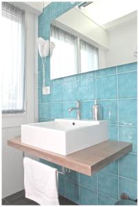 baño con lavabo blanco y azulejos azules en Hotel Dante, en Lido di Jesolo