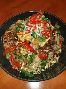 a black plate of food with noodles and vegetables at Dampier Mermaid Hotel Karratha in Dampier