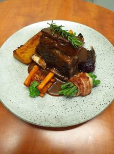 ein Teller mit Fleisch und Gemüse auf dem Tisch in der Unterkunft Dampier Mermaid Hotel Karratha in Dampier